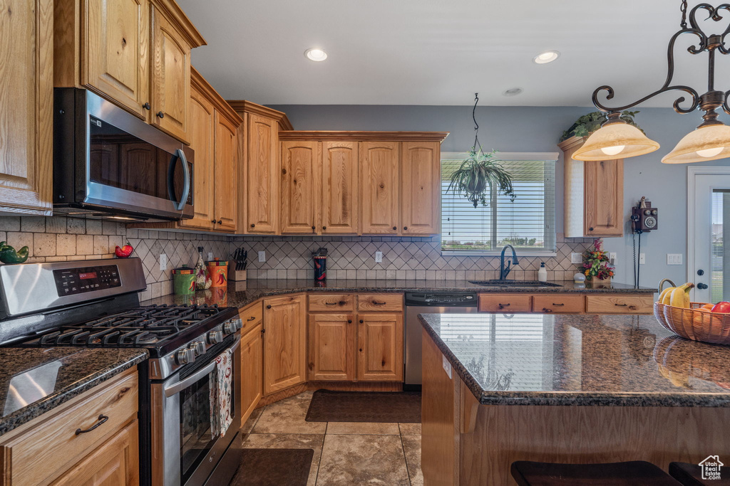 Kitchen featuring appliances with stainless steel finishes, decorative backsplash, dark stone counters, recessed lighting, and pendant lighting