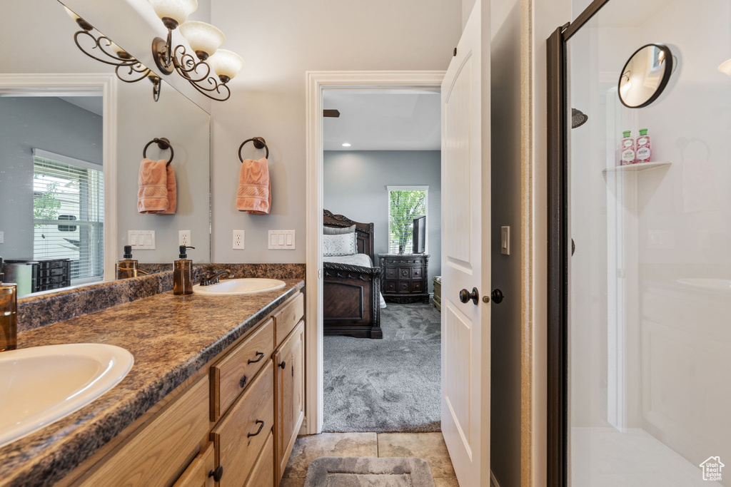 Full bathroom with connected bathroom, double vanity, a stall shower, a chandelier, and tile patterned floors