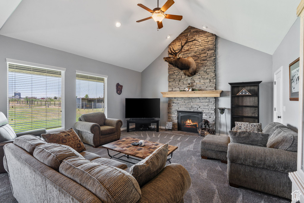 Living room with a ceiling fan, a stone fireplace, carpet floors, and high vaulted ceiling