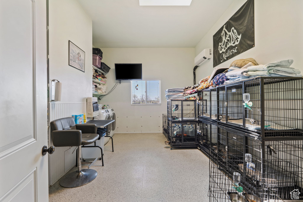Office space featuring a wall mounted air conditioner, speckle patterned floor, and washer / dryer