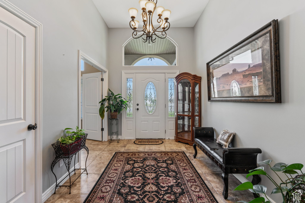 Tiled entrance foyer featuring a chandelier and a towering ceiling