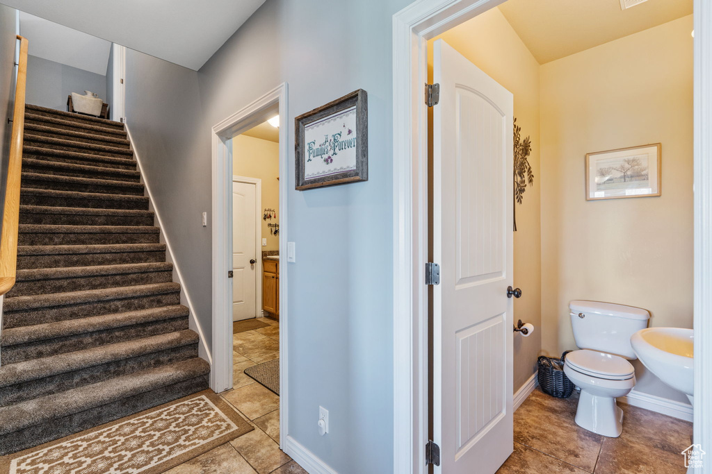 Stairway with tile patterned floors and baseboards