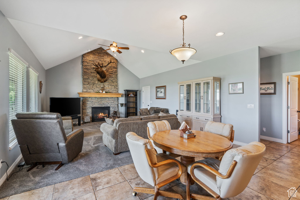 Dining area with ceiling fan, a stone fireplace, lofted ceiling, light tile patterned flooring, and recessed lighting