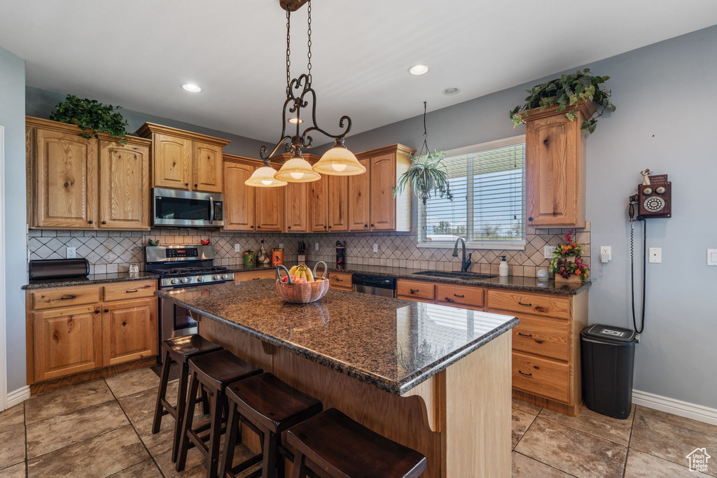 Kitchen featuring stainless steel appliances, decorative backsplash, a kitchen breakfast bar, a kitchen island, and decorative light fixtures