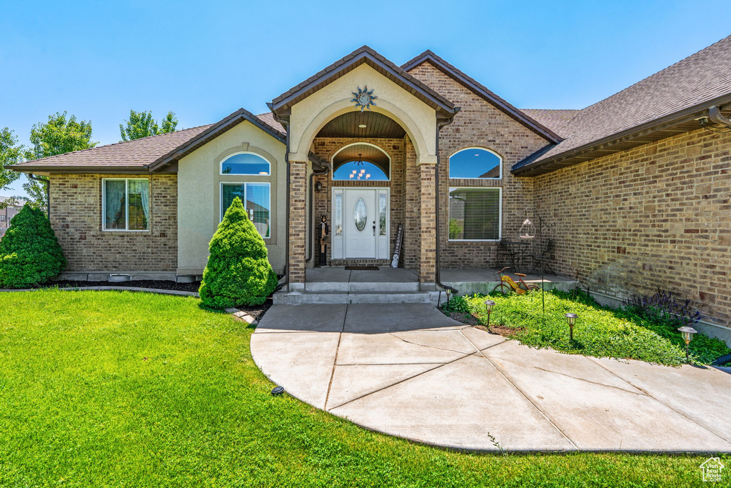 View of exterior entry featuring brick siding and a yard