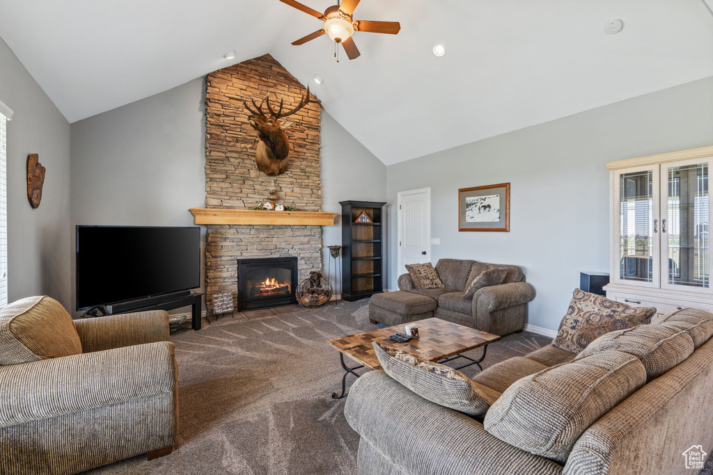 Living room with ceiling fan, carpet, high vaulted ceiling, and a stone fireplace