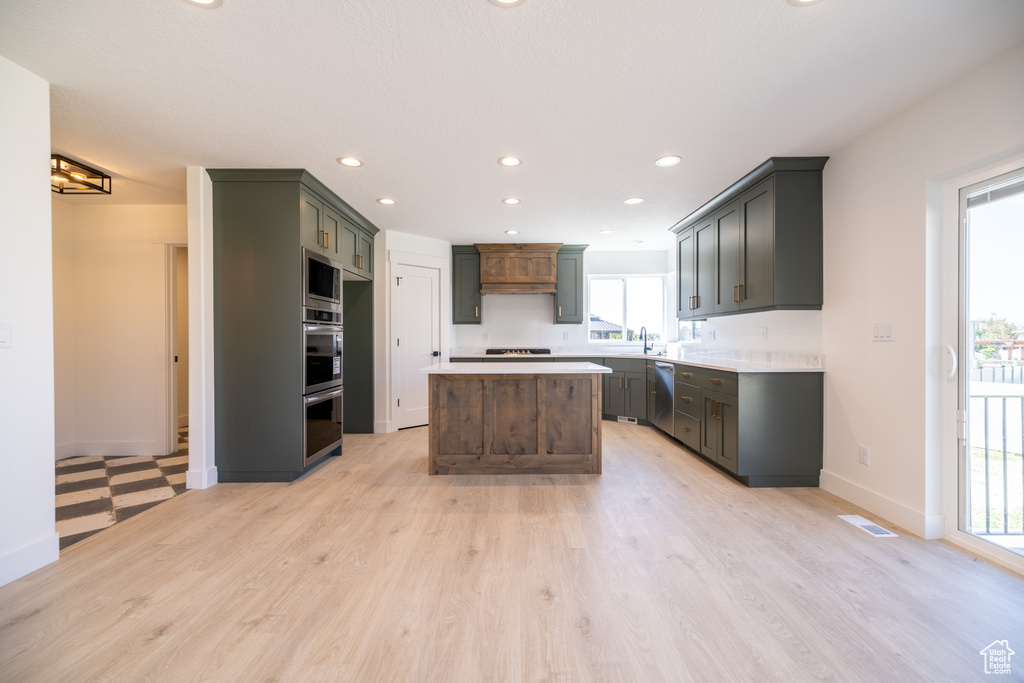 Kitchen featuring stainless steel appliances, recessed lighting, light wood-style floors, light countertops, and a center island