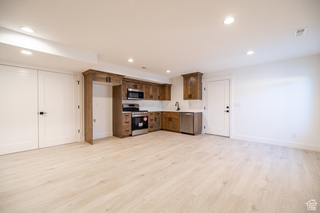 Kitchen featuring appliances with stainless steel finishes, recessed lighting, light wood-style floors, and light countertops