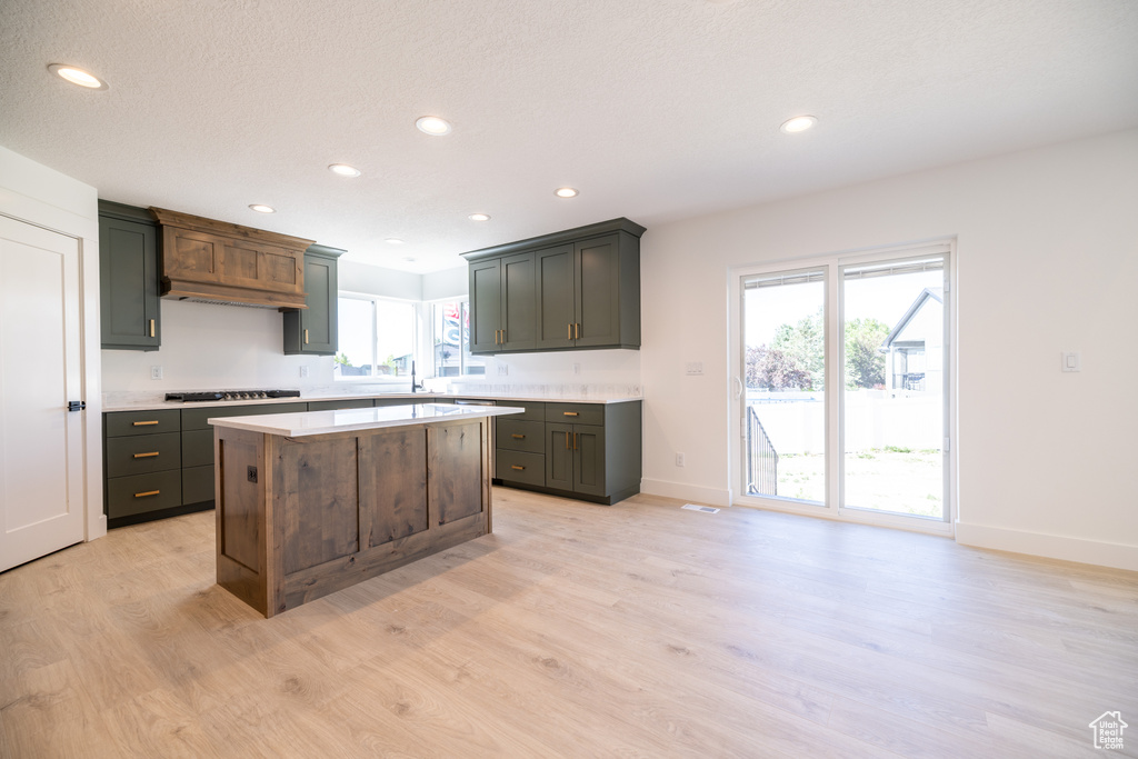Kitchen with gas stovetop, light wood-style floors, light countertops, recessed lighting, and a kitchen island