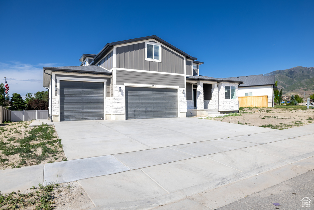 View of front of home featuring board and batten siding, driveway, an attached garage, and a mountain view