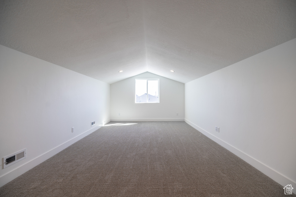 Additional living space with lofted ceiling and dark carpet