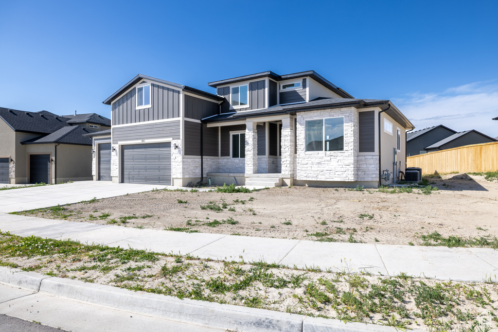 View of front of property with stone siding, driveway, board and batten siding, and a garage