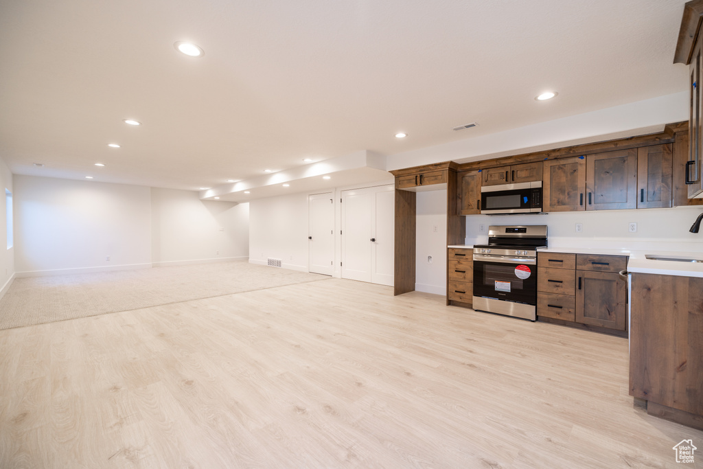 Kitchen featuring stainless steel appliances, light countertops, light wood-type flooring, and recessed lighting