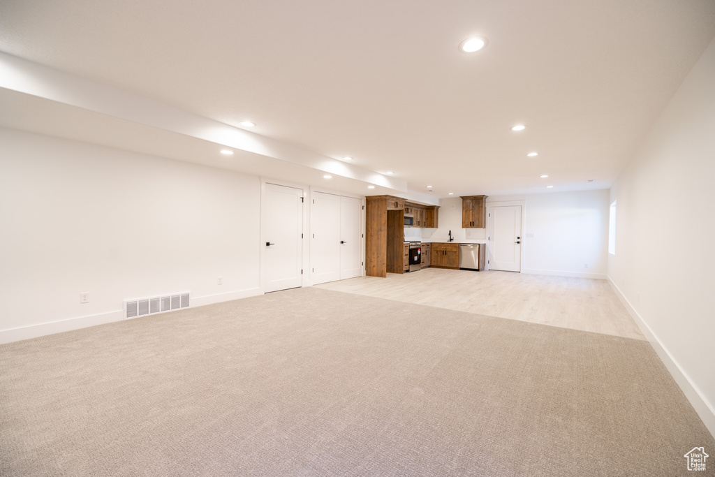 Unfurnished living room with recessed lighting, light colored carpet, and wet bar