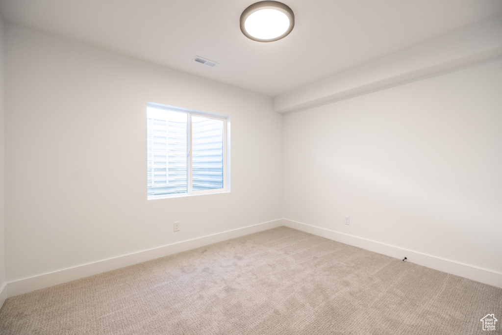 Empty room with light colored carpet and baseboards