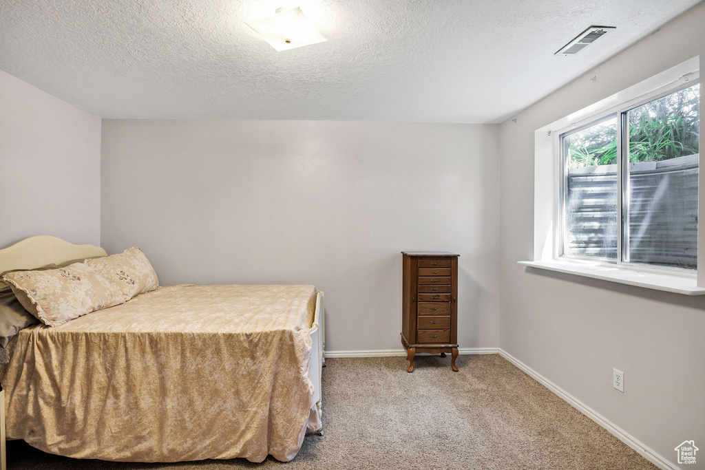 Bedroom with a textured ceiling and carpet flooring
