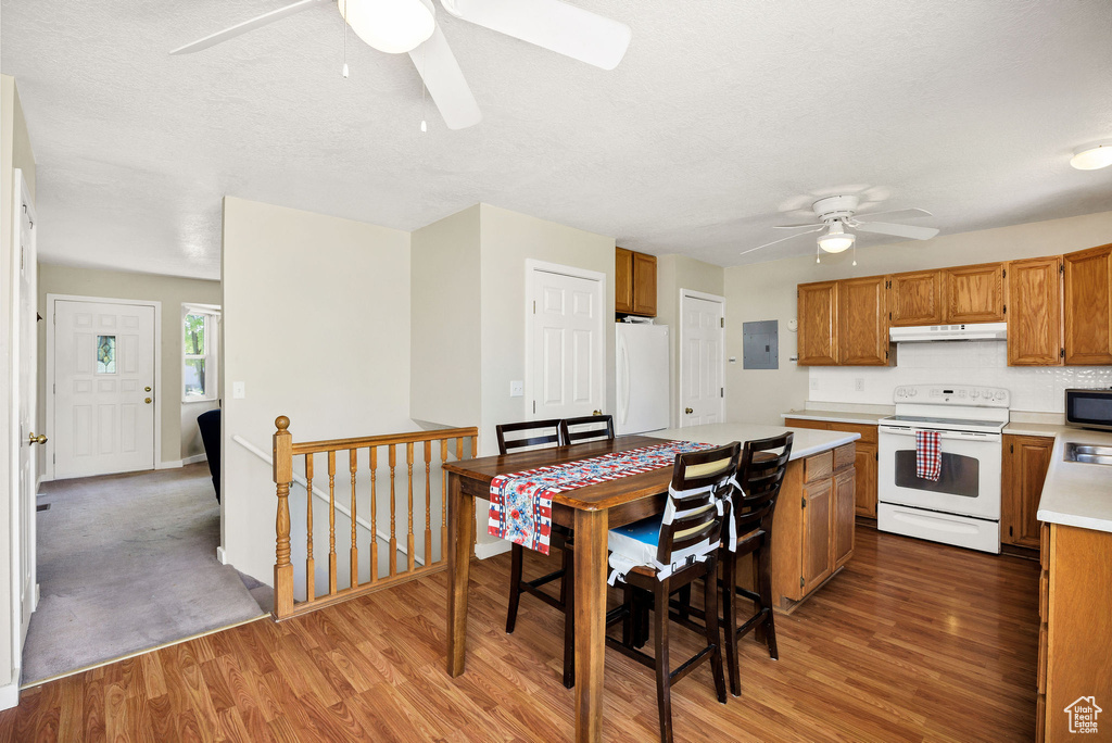 Kitchen with white appliances, a ceiling fan, light countertops, light wood finished floors, and under cabinet range hood