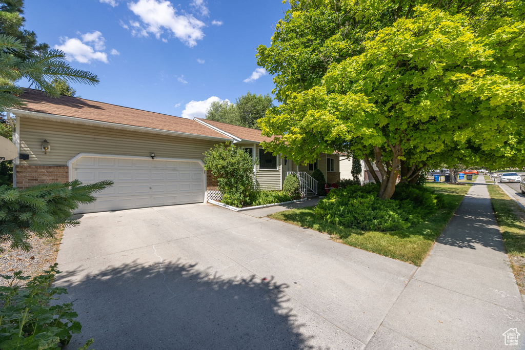 View of front of property featuring a garage, concrete driveway, and brick siding
