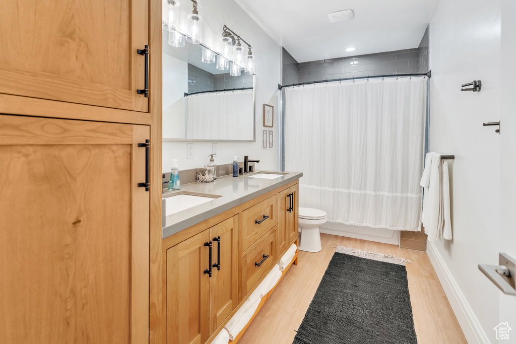 Full bathroom featuring wood finished floors, double vanity, and shower / bath combination with curtain
