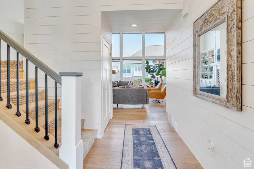 Hall featuring light wood finished floors, stairway, and wooden walls