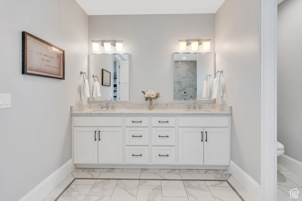Full bathroom featuring marble finish flooring, a marble finish shower, and double vanity