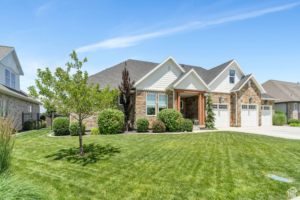 View of front of property with concrete driveway, an attached garage, stone siding, and a shingled roof