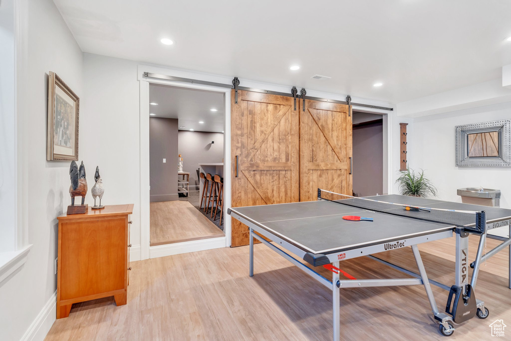 Recreation room featuring light wood-style floors, a barn door, and recessed lighting