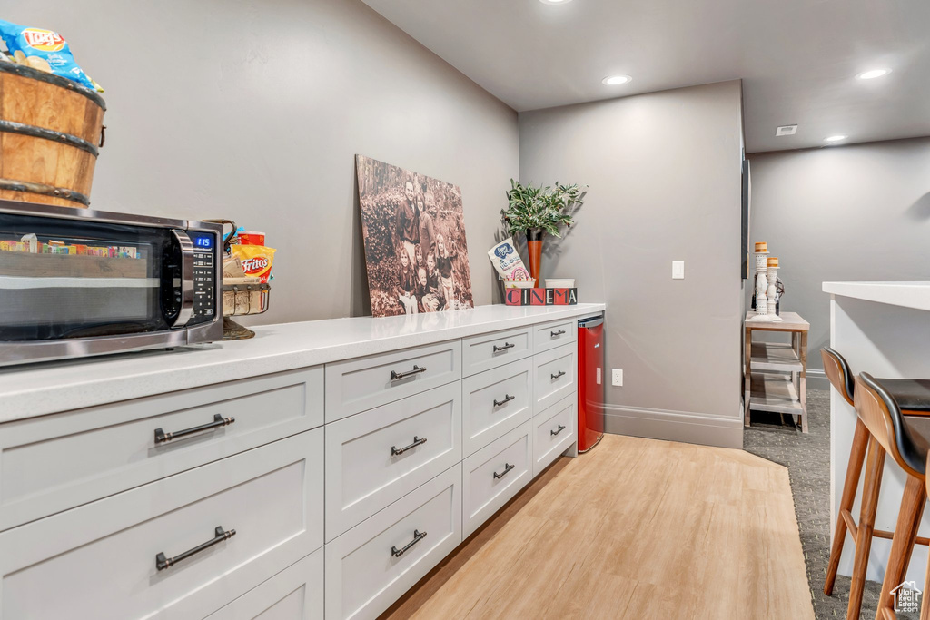 Kitchen with stainless steel microwave, recessed lighting, light countertops, white cabinetry, and light colored carpet