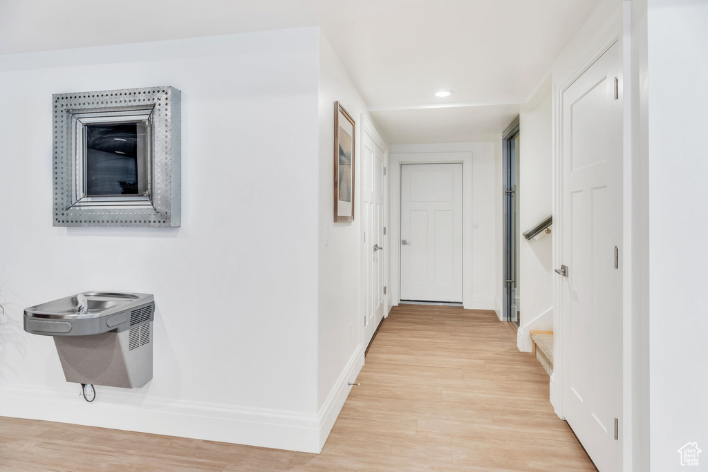 Hallway featuring light wood-style flooring, stairs, and recessed lighting
