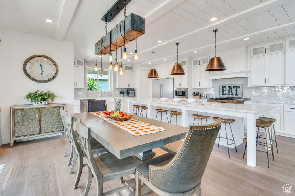 Dining space with beamed ceiling, light wood-style floors, and recessed lighting