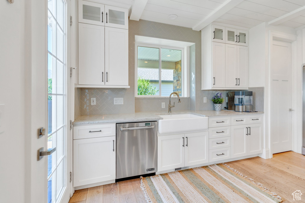Kitchen with dishwasher, light wood finished floors, beam ceiling, backsplash, and white cabinets