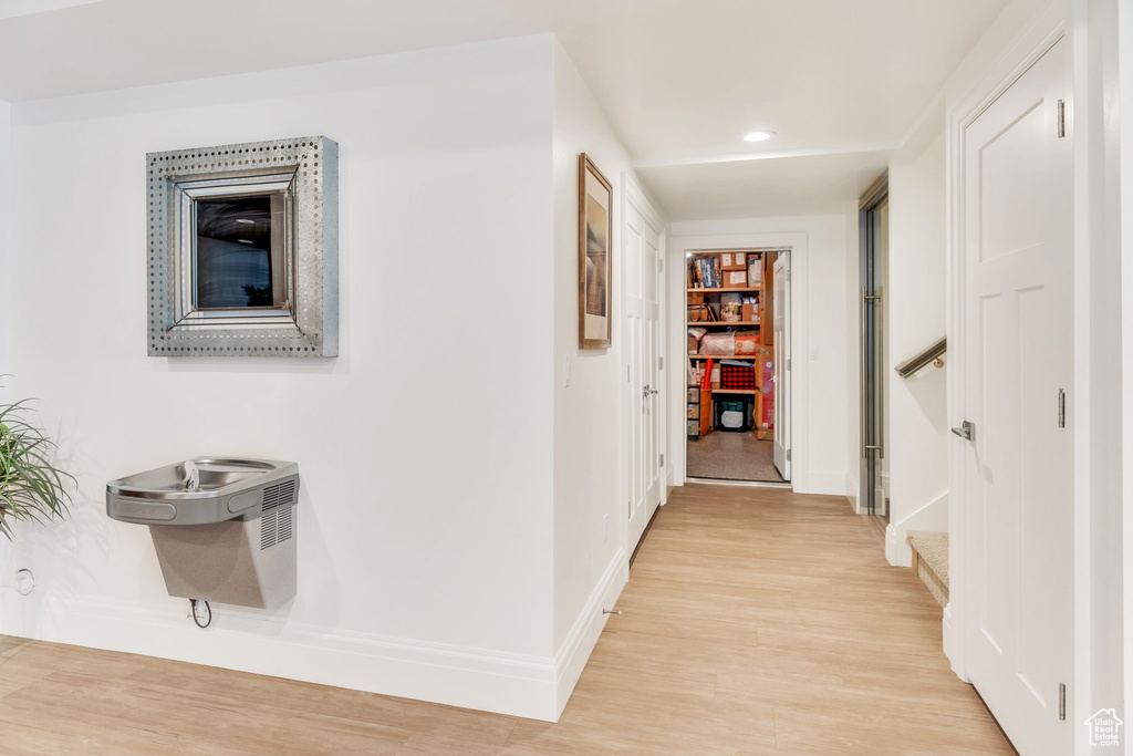 Hall with light wood-style floors and recessed lighting