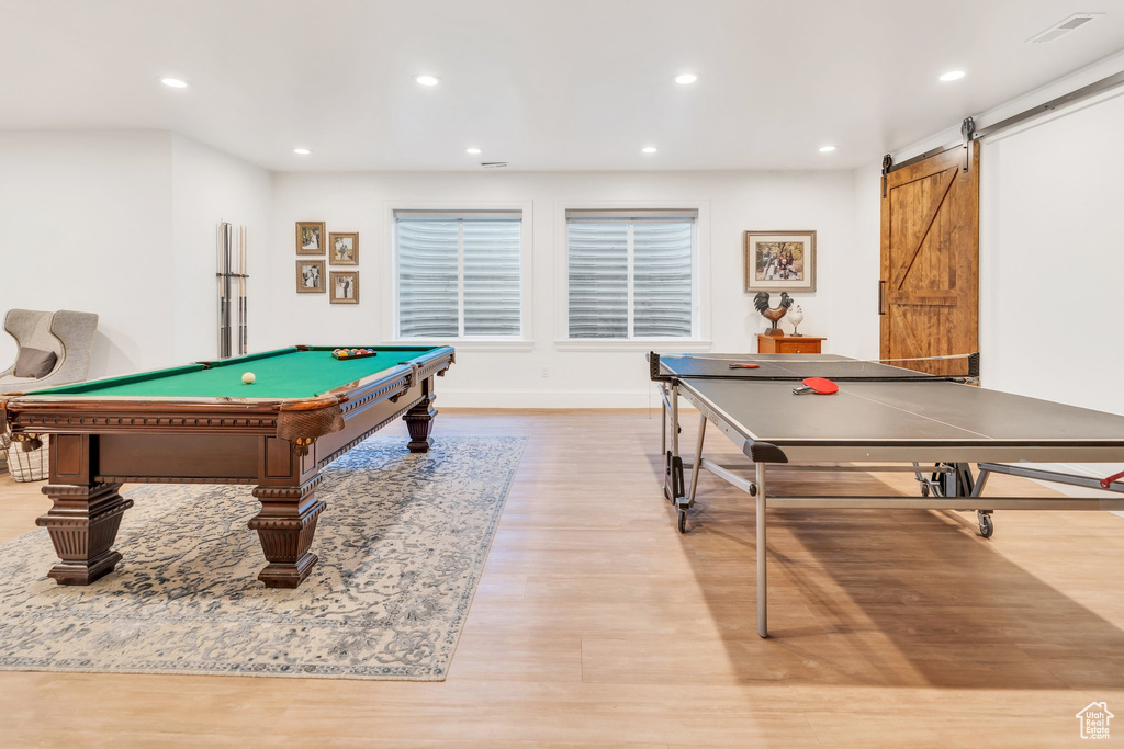 Recreation room with wood finished floors, a barn door, recessed lighting, and billiards