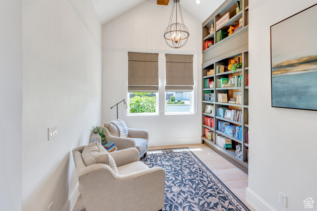 Living area with a chandelier, light wood-type flooring, and vaulted ceiling