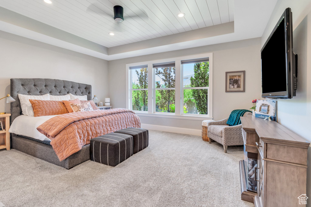 Carpeted bedroom with a raised ceiling, recessed lighting, and wood ceiling