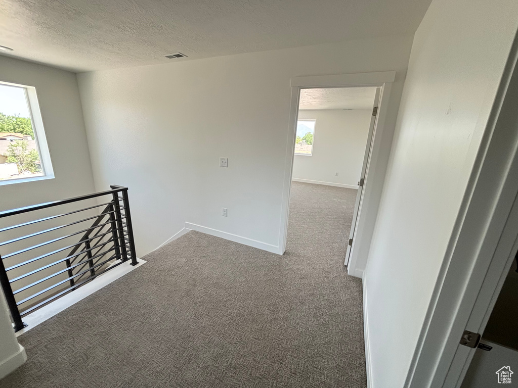 Carpeted spare room with a textured ceiling and baseboards