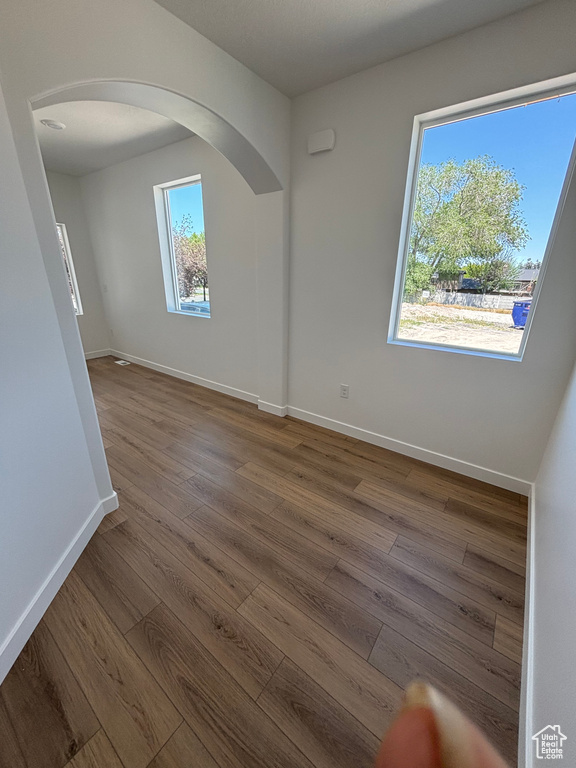 Unfurnished room with arched walkways and dark wood-style flooring