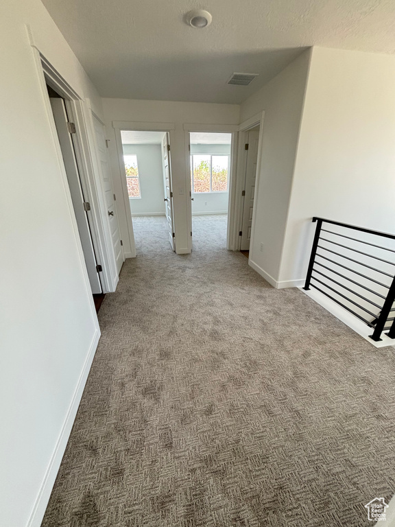 Corridor featuring carpet flooring and an upstairs landing