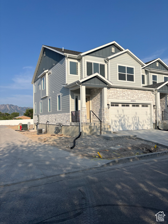 View of front of property with board and batten siding, an attached garage, stone siding, driveway, and a mountain view