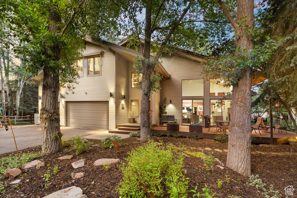 View of front of house with concrete driveway, a garage, and a deck