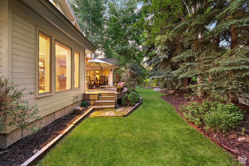 View of grassy yard featuring a wooden deck