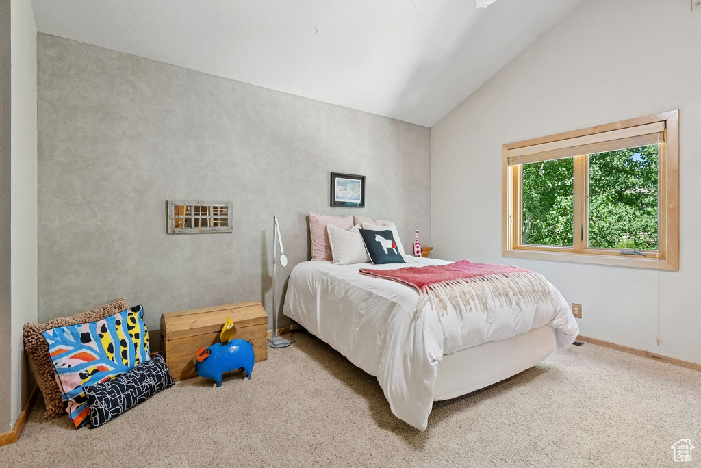 Carpeted bedroom with lofted ceiling and baseboards