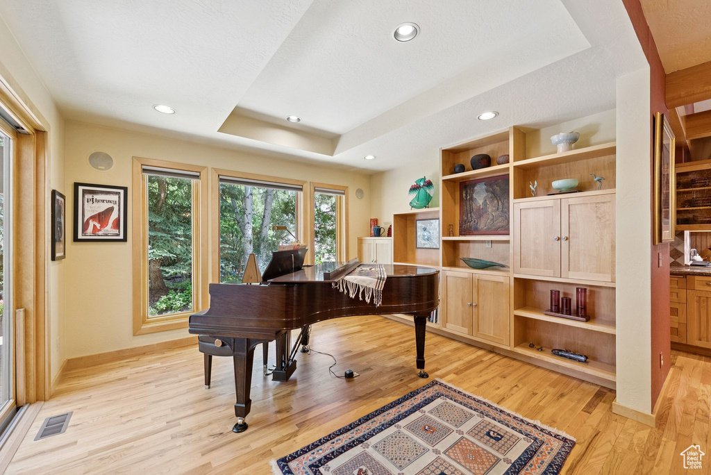 Office space featuring light wood finished floors, a tray ceiling, and recessed lighting