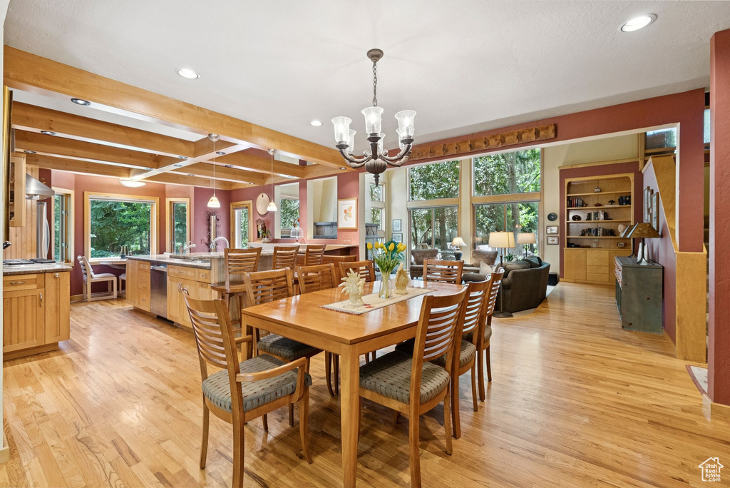 Dining room featuring recessed lighting, light wood-type flooring, healthy amount of natural light, a chandelier, and beam ceiling