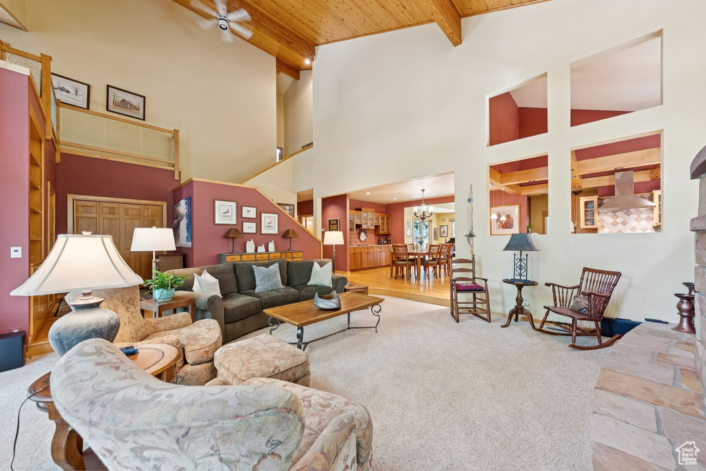Carpeted living area featuring a wooden ceiling with exposed beams, a chandelier, and a towering ceiling