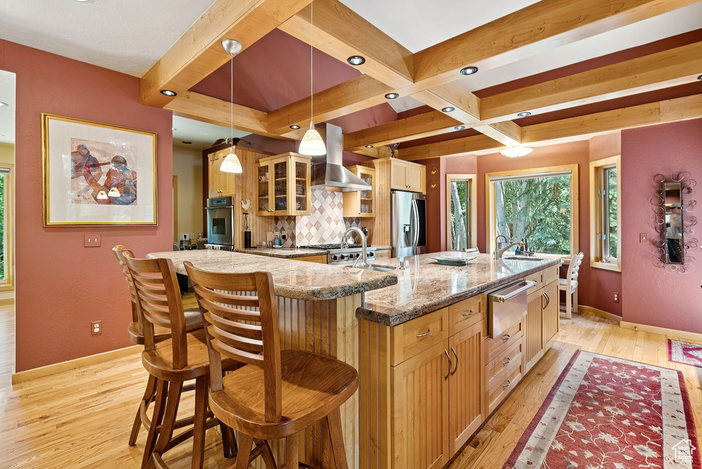 Kitchen featuring range hood, a large island, a warming drawer, appliances with stainless steel finishes, and decorative backsplash