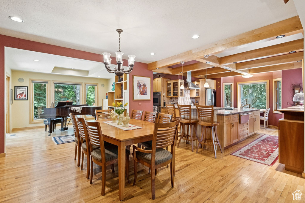 Dining space with light wood-style floors, a chandelier, recessed lighting, and beamed ceiling