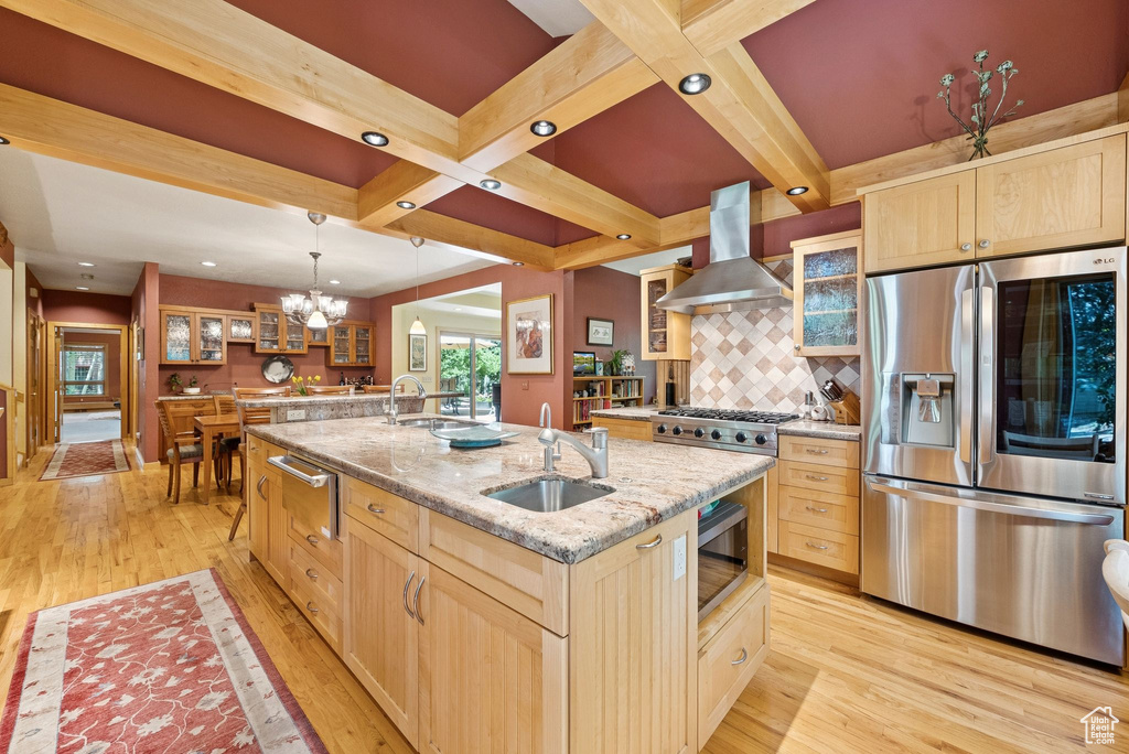 Kitchen featuring stainless steel appliances, island range hood, light brown cabinets, an island with sink, and recessed lighting