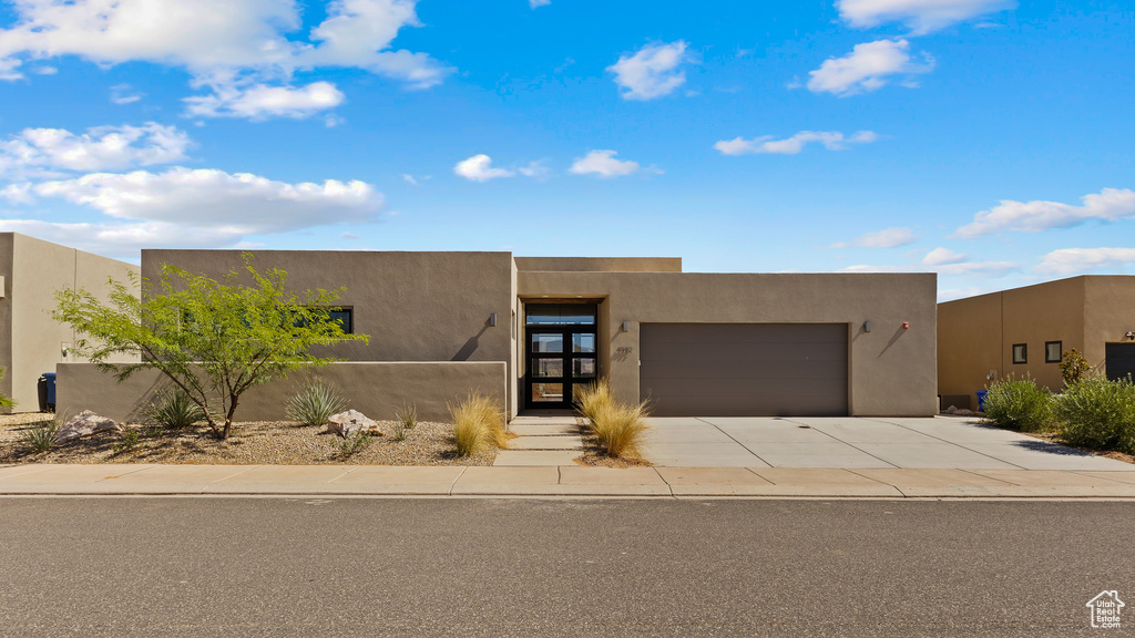 Pueblo revival-style home with an attached garage, concrete driveway, and stucco siding