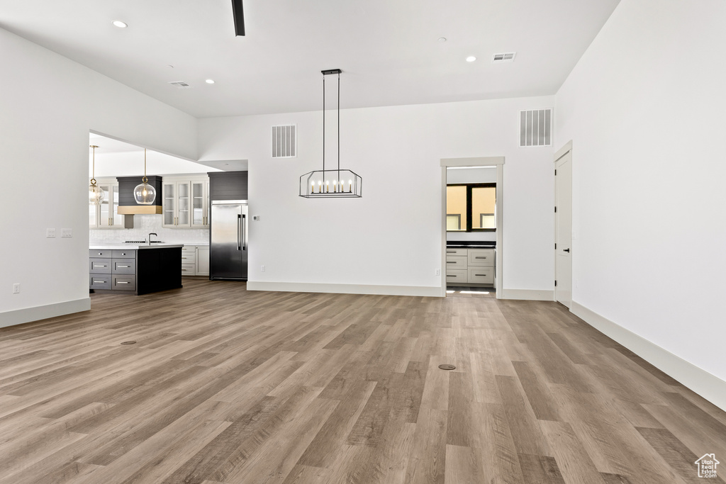 Unfurnished living room featuring light wood-style flooring, a chandelier, and recessed lighting